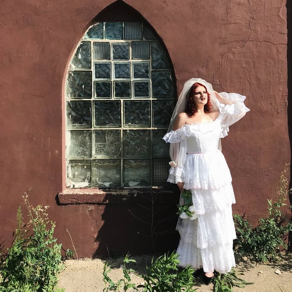 Woman in wedding dress in front of a church looks upset