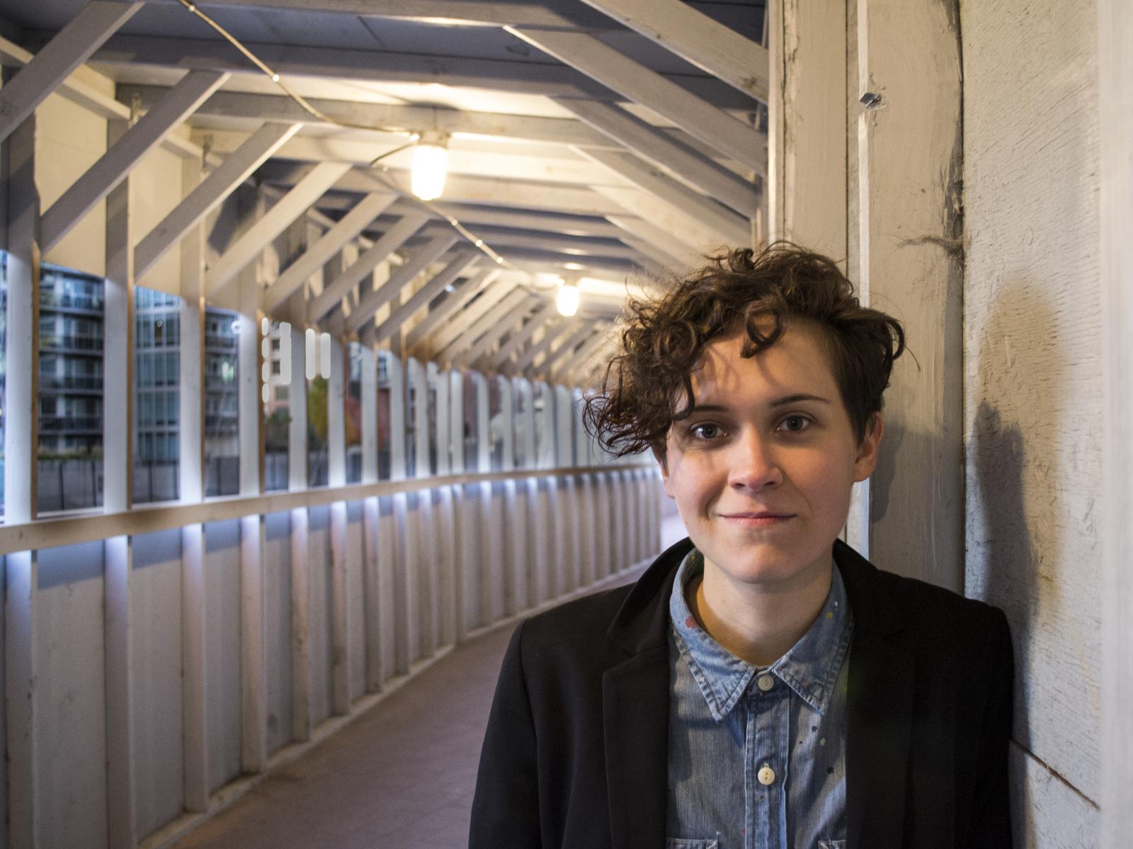 Person in suit jacket and collared shirt leaning against the wall of a tunnel